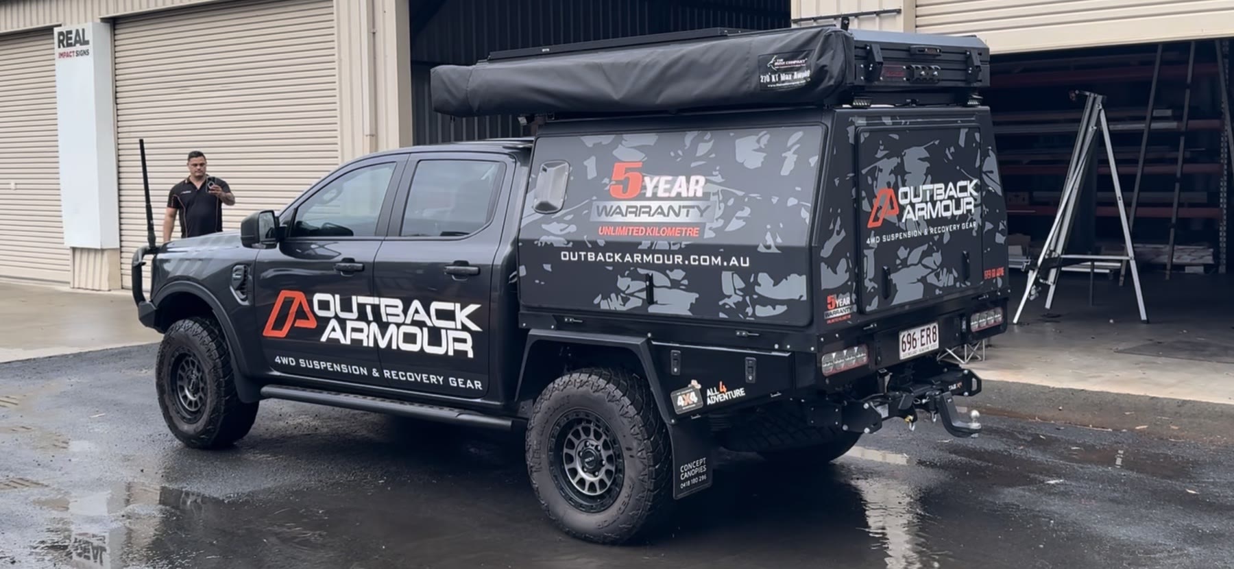 Outback Armour four-wheel-drive ute with charcoal camouflage and red-and-white vehicle graphics