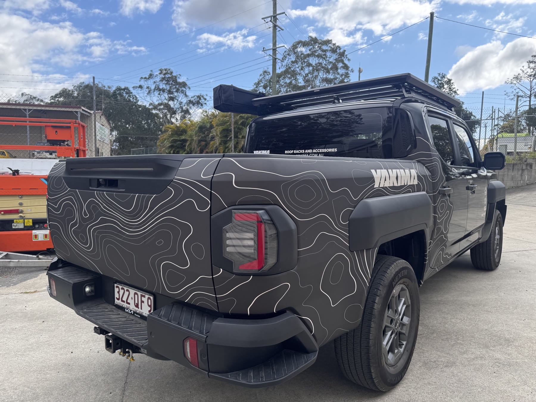 Side view of a dark grey ute with white contour-line graphics wrapping around the rear panels